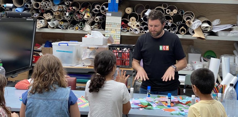 Ben Segal showing school-aged children what they are about to do with glue and paper