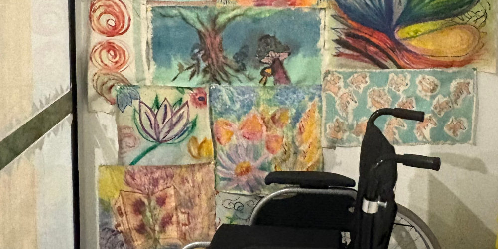 Wheelchair in front of a wall of paintings